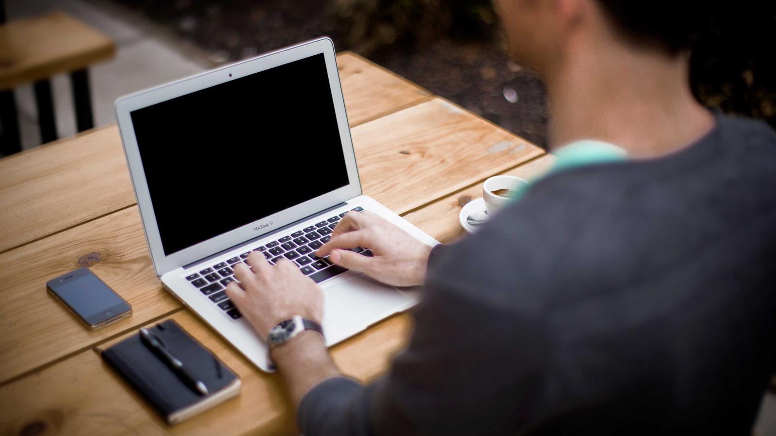 Person typing on a laptop at a wooden desk